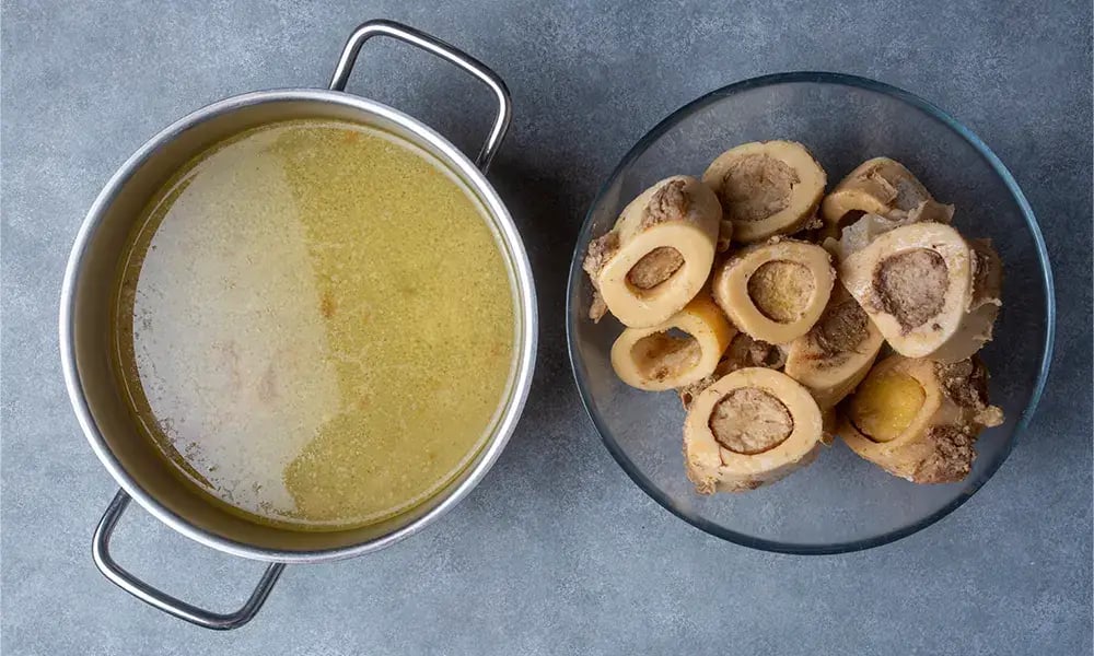 A pot of rich bone broth next to a bowl of bone marrow, potential products from Gingin Grass Fed in Gingin, WA.