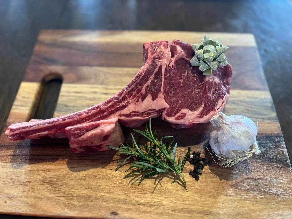 A beautifully presented raw Tomahawk steak with rosemary and garlic from Heritage Farms Tasmania.