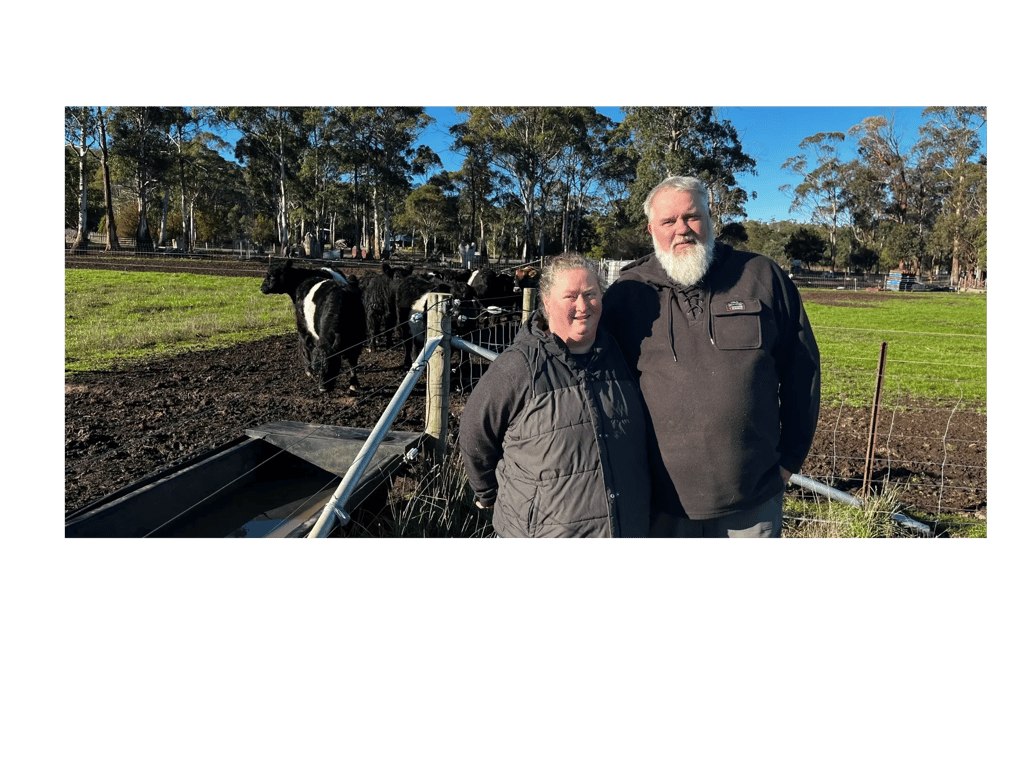 Two farmers, a man and a woman, standing in a paddock with black and white cows at Heritage Farms Tasmania.