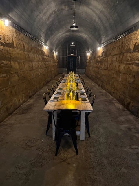 A long dining table set for guests inside the illuminated historic tunnel at Tunnel Hill Mushrooms in Tasmania.