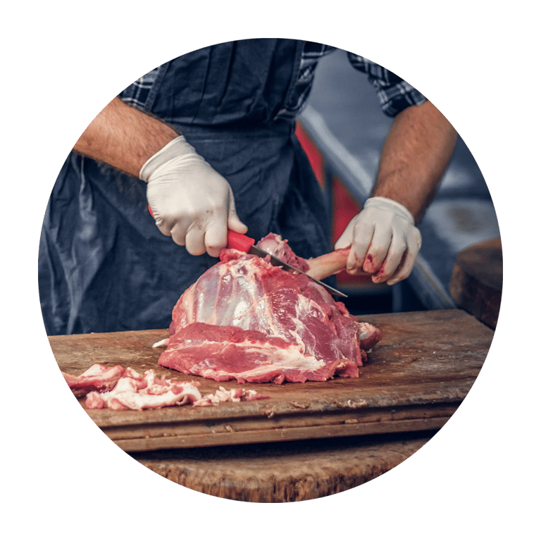 Raw lamb chops and a large cleaver on a black slate board, garnished with rosemary and sea salt.
