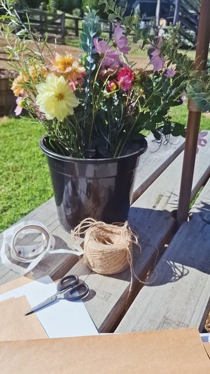 Craft supplies and a pot of colourful cut flowers on a wooden table at Cedar Creek Farm, Wollombi Valley.